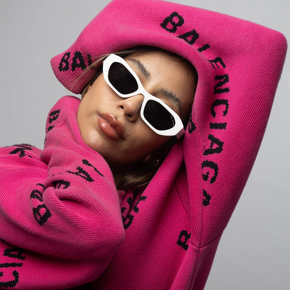 Person wearing a bright pink outfit with 'Balenciaga' branding on a gray background